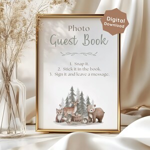 May include: A gold-framed sign with the text Photo Guest Book and instructions: 1. Snap it. 2. Stick it in the book. 3. Sign it and leave a message. The design features a watercolor illustration of a deer, bear, fox, and trees at the bottom.
