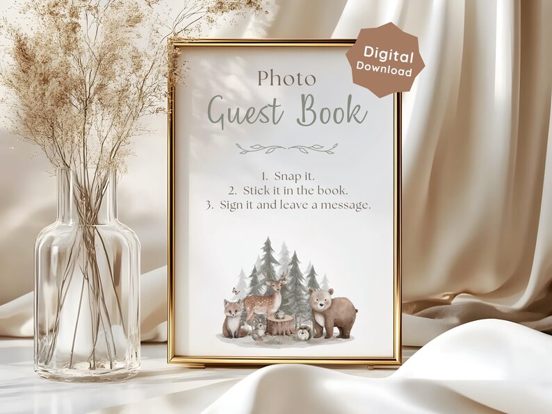 May include: A gold-framed sign with the text Photo Guest Book and instructions: 1. Snap it. 2. Stick it in the book. 3. Sign it and leave a message. The design features a watercolor illustration of a deer, bear, fox, and trees at the bottom.
