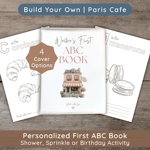 May include: A personalized ABC book with a Paris cafe illustration on the cover, flanked by two coloring pages featuring a croissant and macarons. The text reads Build Your Own Paris Cafe, Walker's First ABC BOOK, 4 Cover Options, and Made with Love.