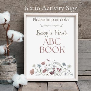 An 8x10 inch framed "Baby’s First ABC Book" activity sign that says "Please help us color." It is styled next to a glass jar with cotton stems on a rustic wooden background.