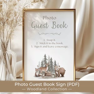 May include: A rectangular gold-framed sign with white background featuring the text Photo Guest Book, instructions to snap, stick, and sign, and a watercolor illustration of a fox, deer, bear, and hedgehog in a forest setting.