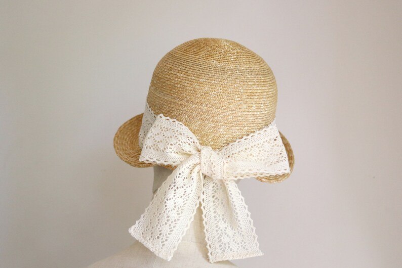 A straw hat with a wide brim and a large white lace bow tied at the back.
