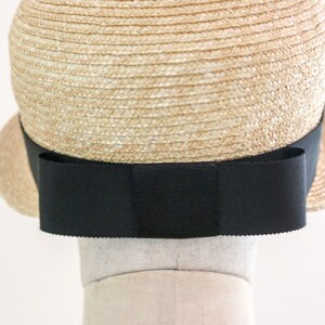 A straw hat with a wide brim and a black ribbon tied in a bow at the back.