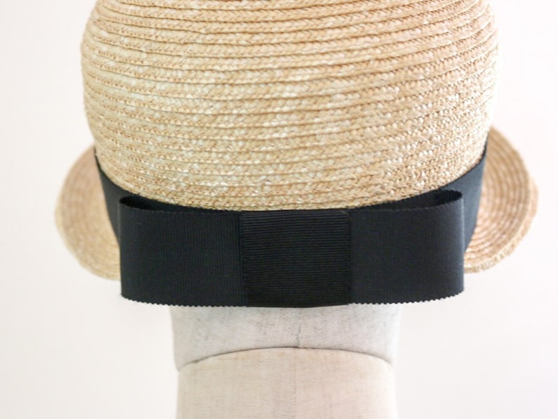 A straw hat with a wide brim and a black ribbon tied in a bow at the back.