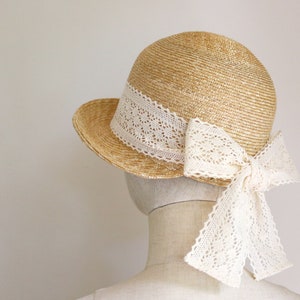 A straw hat with a wide brim and a white lace ribbon tied in a bow at the back.
