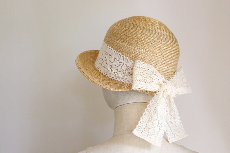 A straw hat with a wide brim and a white lace ribbon tied in a bow at the back.