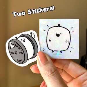 May include: Two stickers, one featuring a cartoon of a white, round character with a black eye and a black mouth, lifting a weight with the text "Gym" and "25lbs" on it. The other sticker features a white, square character with a black eye and a black mouth, with a black dot on top of its head. The background of the sticker is iridescent.