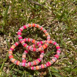 Könnte beinhalten: Drei Armbänder aus rosa, orange und weißen Perlen mit Perlenakzenten.