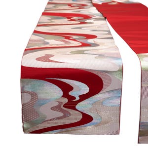 May include: A decorative table runner with a red and white wave pattern. The runner features a vibrant red border and a flowing design in shades of white, gray, and blue. The fabric has a subtle sheen.