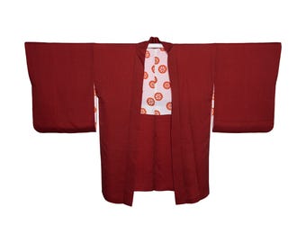 May include: A dark red kimono with a textured surface and wide sleeves. The interior lining is white and features a repeating pattern of orange circular motifs that resemble stylized wheels or flowers, visible at the collar and sleeve openings.