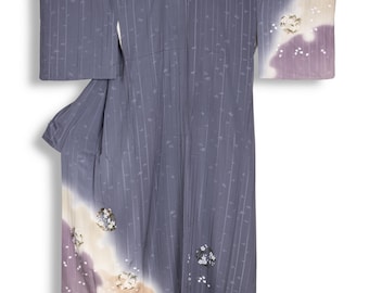 May include: A gray kimono with vertical stripes and floral accents. The sleeves and lower portion feature a gradient of lavender, beige, and white. Small, white floral patterns are scattered across the garment.