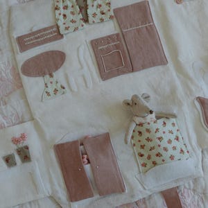 Puede incluir: Un juguete de tela blanca con detalles rosas y estampados florales. Incluye una mesa, cortinas y un rat&oacute;n de juguete. El juguete tiene un asa y est&aacute; dise&ntilde;ado para ni&ntilde;os.