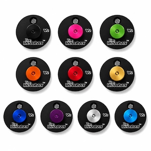 May include: Ten circular black discs labeled The Revolver V2, each featuring a small central button in a different color: black, pink, green, orange, red, gold, blue, purple, silver, and light blue, with a small gear icon above the button.