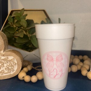 May include: White foam cup with a pink bow and the number 22 in a circle.