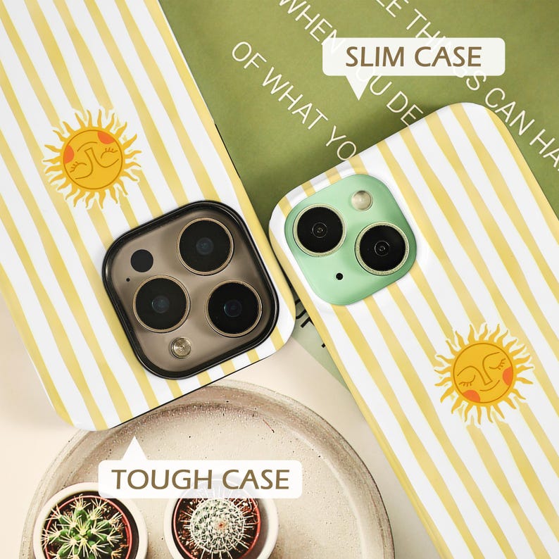 May include: Two phone cases with a yellow and white striped pattern and a smiling sun graphic. One case is labeled "SLIM CASE" and the other is labeled "TOUGH CASE". The phone cases have different camera designs.
