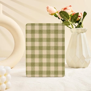 May include: A rectangular electronic reader cover featuring a sage green and cream-colored gingham check pattern. The cover has a flat, matte surface with a consistent grid design across the entire front face of the device protector.