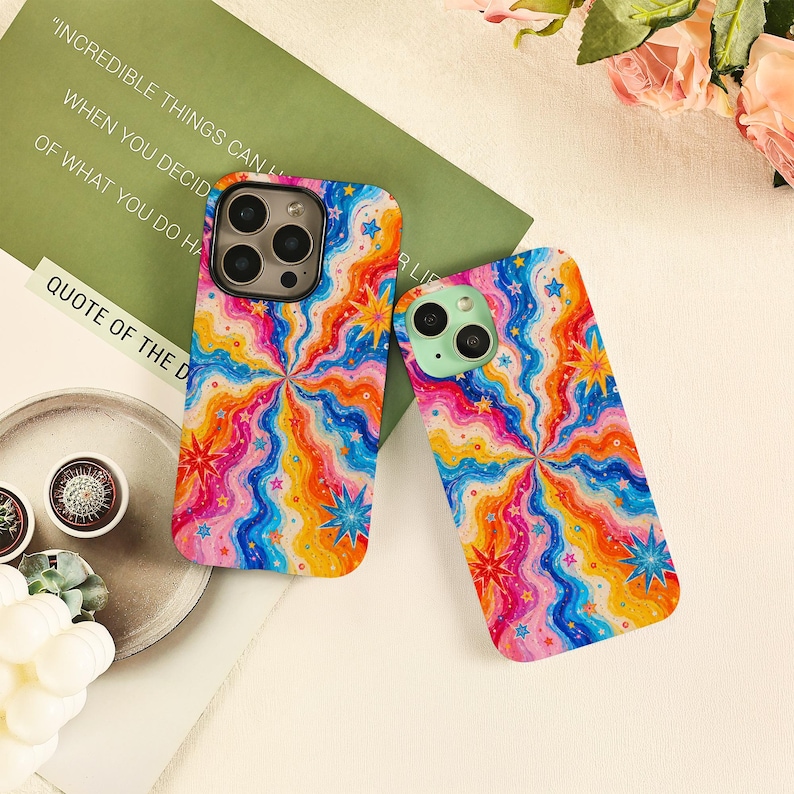 May include: Two smartphone cases featuring a vibrant, multi-colored wavy pattern in shades of blue, orange, yellow, and pink. The design includes scattered star shapes throughout the swirling lines. Each case has a camera cutout on the back.
