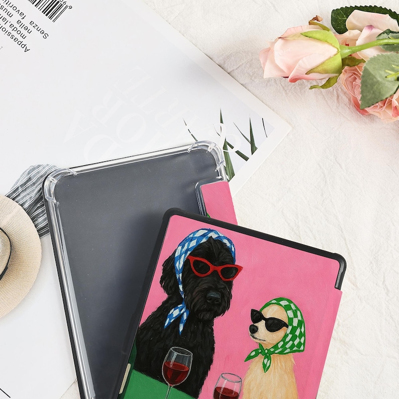 Pu&ograve; includere: Una custodia rosa per tablet con un cane nero con occhiali da sole rossi e un foulard blu, e un cane marrone chiaro con occhiali da sole neri e un foulard verde. Entrambi i cani tengono in mano dei calici di vino. Dietro la custodia rosa c'&egrave; una custodia trasparente per tablet.