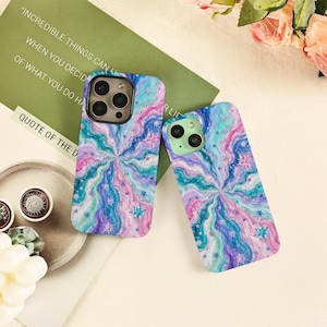 May include: Two rectangular phone cases featuring a swirling, psychedelic pattern in shades of blue, purple, pink, and teal. The design includes small, star-shaped accents scattered throughout the wavy, marbled texture on both protective covers.