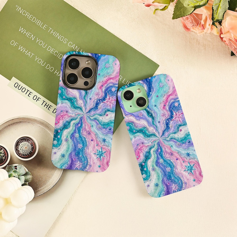 May include: Two rectangular phone cases featuring a swirling, psychedelic pattern in shades of blue, purple, pink, and teal. The design includes small, star-shaped accents scattered throughout the wavy, marbled texture on both protective covers.