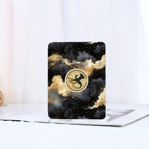 May include: A black and gold phone case with a watercolour design of clouds and stars. A gold circle with a black silhouette of a dragon is in the centre of the case.