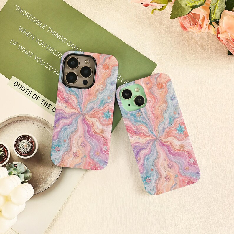 May include: Two smartphone cases featuring a swirling, marbled pattern in pastel shades of pink, blue, and orange. The designs include small, scattered star-like accents. One case has a dark camera housing, while the other has a light green housing.