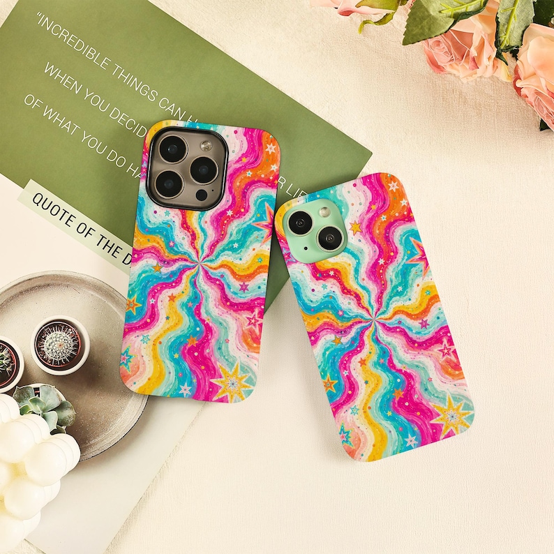 May include: Two phone cases featuring a vibrant, multi-colored wavy radial pattern in shades of pink, yellow, and turquoise, accented with small yellow and white star shapes. The designs cover the entire back surface of both rectangular phone cases.