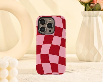 Puede incluir: Una funda de teléfono con un patrón de tablero de ajedrez rojo y rosa. La funda tiene un recorte para la cámara y está diseñada para adaptarse a un teléfono inteligente. La funda está hecha de un material liso y tiene un acabado brillante.