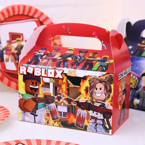 May include: Red Roblox-themed party favor box with a handle, featuring Roblox characters and the Roblox logo. The box has a colorful design with images of characters holding weapons and a burning house.