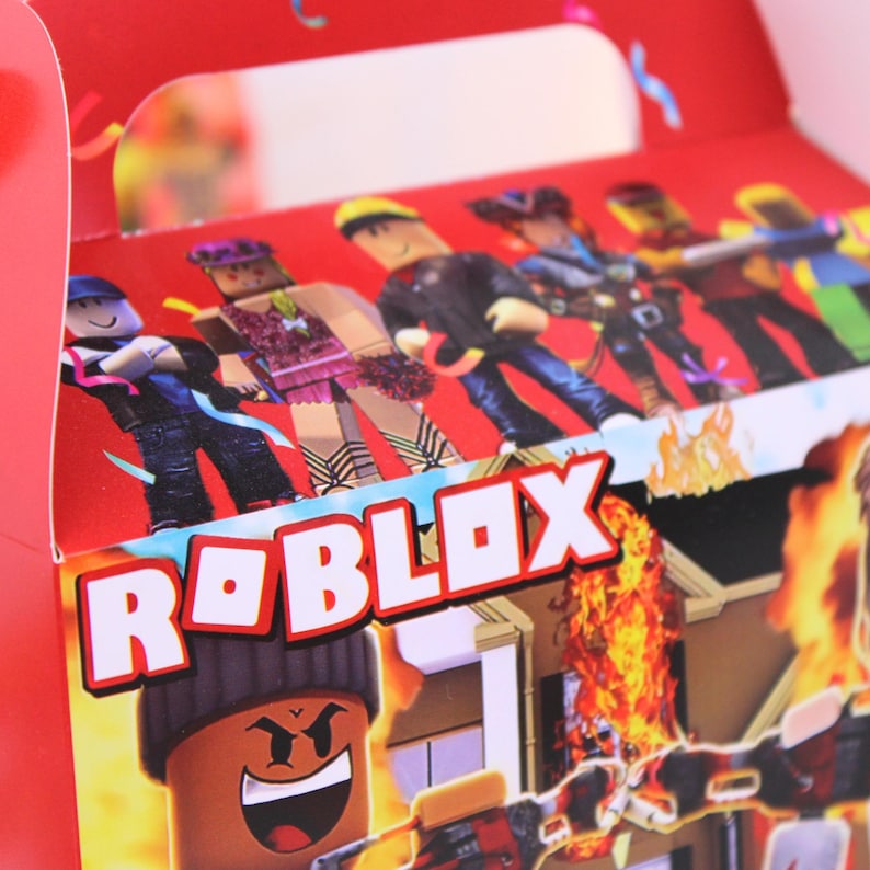 May include: Red Roblox-themed gift box featuring Roblox characters and the Roblox logo in white. The box has a handle and is decorated with images of characters and a burning building. The overall design is vibrant and eye-catching.