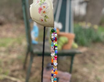 Vindklocka och solfångare i krämfärgad blommig tekopp - färgglada runda pärlor