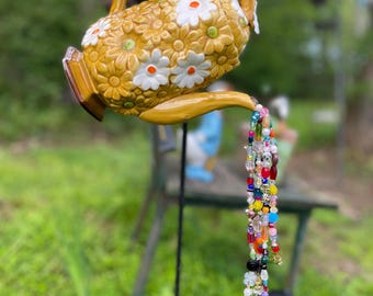 Campanilla de viento y atrapasueños con forma de tetera de caramelo y flores blancas.
