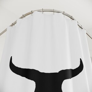 May include: White shower curtain with a black silhouette of a bull's head.