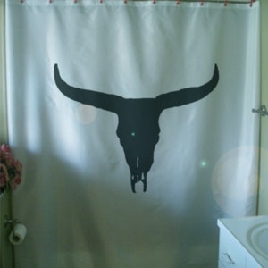 May include: White shower curtain with a black silhouette of a bull skull.