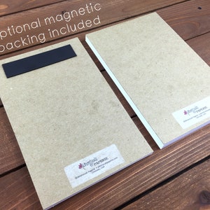 May include: Two rectangular notepads with optional magnetic backing. One notepad has a black magnetic strip attached. The notepads are light brown with white edges and a small label in the bottom corner. The text "Optional magnetic backing included" is visible.