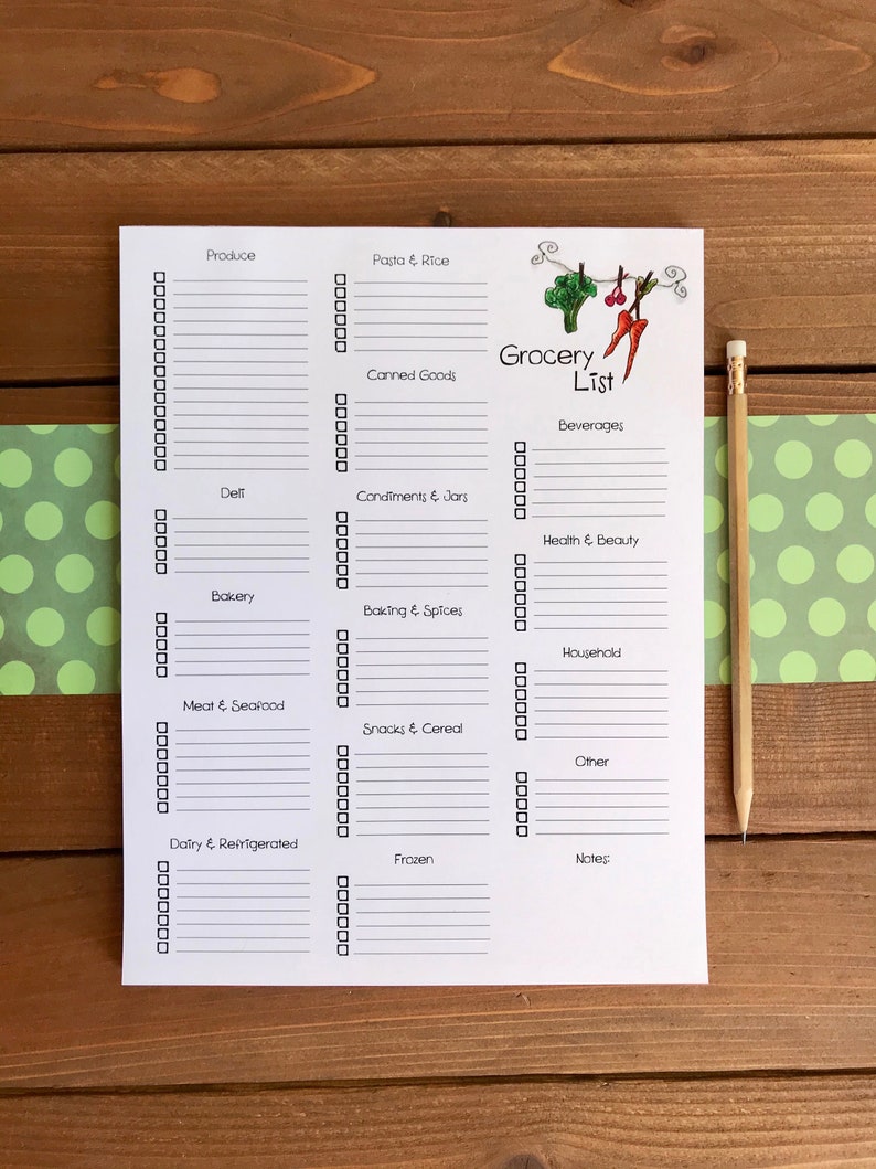 May include: A white paper grocery list with sections for produce, dairy, and other items. The list has a decorative illustration of vegetables and the words "Grocery List". A pencil rests on the wooden surface.