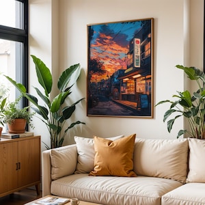 Puede incluir: Un sof&aacute; beige con un coj&iacute;n de color mostaza en una sala de estar con una gran impresi&oacute;n enmarcada de una escena de calle de la ciudad al atardecer. La impresi&oacute;n presenta un edificio con un letrero circular rojo y el texto "Restaurante" en japon&eacute;s. Hay dos plantas grandes en macetas en la habitaci&oacute;n.