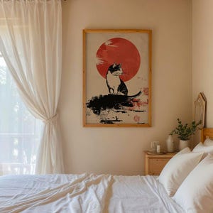 May include: A black and white illustration of a cat sitting in front of a red sun on a white background. The illustration is framed in a wooden frame.
