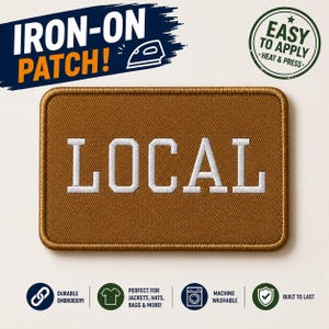 May include: A rectangular iron-on patch with a brown background and a stitched border. The word LOCAL is embroidered in white capital letters across the center. The patch features a durable, machine-washable design intended for application with heat.