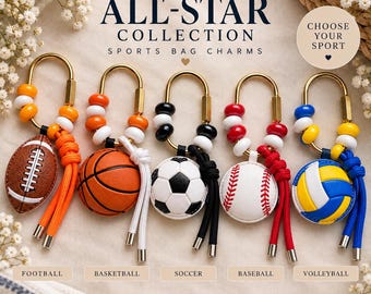 May include: Five sports bag charms featuring miniature football, basketball, soccer, baseball, and volleyball balls attached to gold-toned oval carabiners with colorful beads and cords. Text reads: The ALL-STAR COLLECTION SPORTS BAG CHARMS.