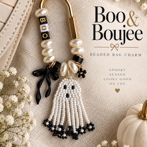 May include: A gold-toned metal carabiner bag charm featuring white pearl-like beads, black spacer beads, and letter beads spelling BOO. A black bow charm, a small black flower charm, and a white beaded ghost pendant with black flower accents hang from the ring.