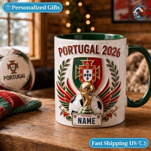 May include: A white ceramic mug with a dark green interior and handle, featuring a raised 3D design of the Portugal shield, a soccer ball, and a gold trophy. The text reads PORTUGAL 2026 and NAME on a license plate graphic with laurel leaves.