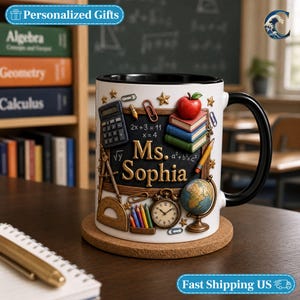 May include: A white ceramic mug with a black handle and interior, featuring a wrap-around graphic of a chalkboard with the text Ms. Sophia, a calculator, a red apple, stacked books, a globe, a clock, pencils, and various school supplies.