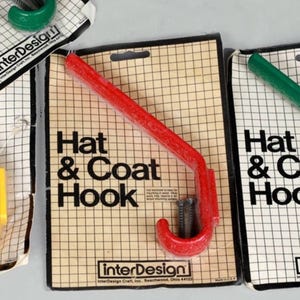 May include: Red plastic hat and coat hook with screws. The packaging says "Hat & Coat Hook" and "interDesign".