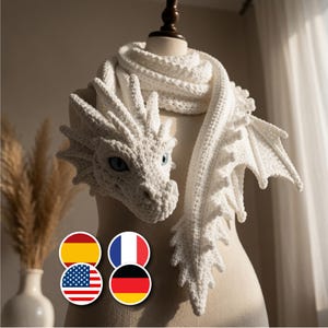 Peut inclure: Une écharpe en crochet blanc en forme de dragon, dotée d'une tête détaillée avec des yeux bleus, des écailles texturées et des ailes pointues le long de l'écharpe. La pièce est réalisée avec une texture de fil épais et entoure un mannequin.