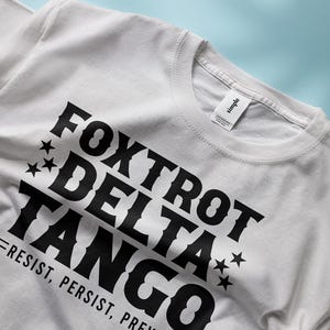 May include: White t-shirt with black text that reads "FOXTROT DELTA TANGO = RESIST, PERSIST, PREV..."