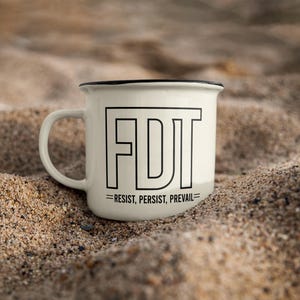 May include: White enamel mug with a black rim and handle. The mug has a black graphic that says "FDT = RESIST, PERSIST, PREVAIL" on the front.
