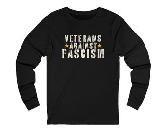 May include: Black long-sleeve shirt with the text "VETERANS AGAINST FASCISM" in distressed white lettering. The text includes two gold stars. The shirt is a crew neck style.