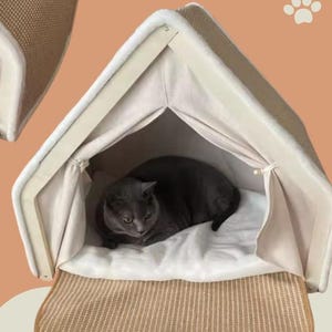 May include: Two cat houses with a beige woven exterior and a cream-colored interior. Each house has a gray cat resting inside on a white cushion. The houses have a roof-like shape and a woven mat at the entrance.