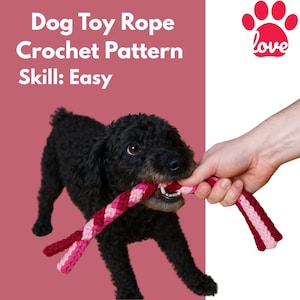 May include: A black dog is playing tug of war with a pink and red crocheted rope toy. The dog is looking at the camera. The background is a pink wall with the text "Dog Toy Rope Crochet Pattern Skill: Easy" and a red paw print with the word "love" in the top right corner.